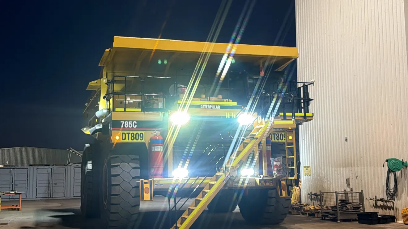 Haul truck lit up under lights in a workshop at night